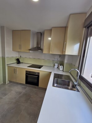A modern kitchen with beige cabinets, a stainless steel sink, and a built-in oven. - Holiday Home 'Santa Pola Centro Con Parking' with Balcony, Wi-Fi and Air Conditioning (Santa Pola)