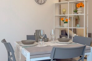 A dining table set with plates, bowls, and glasses, surrounded by chairs. - Bright Studio with A/C and Balcony (Civitanova Marche)