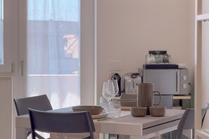 A dining area with a table set for two, a microwave, and a window with curtains. - Bright Studio with A/C and Balcony (Civitanova Marche)