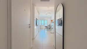 A corridor with a mirrored wall, a dining area with a table and chairs, and pendant lighting. - Bright Studio with A/C and Balcony (Civitanova Marche)