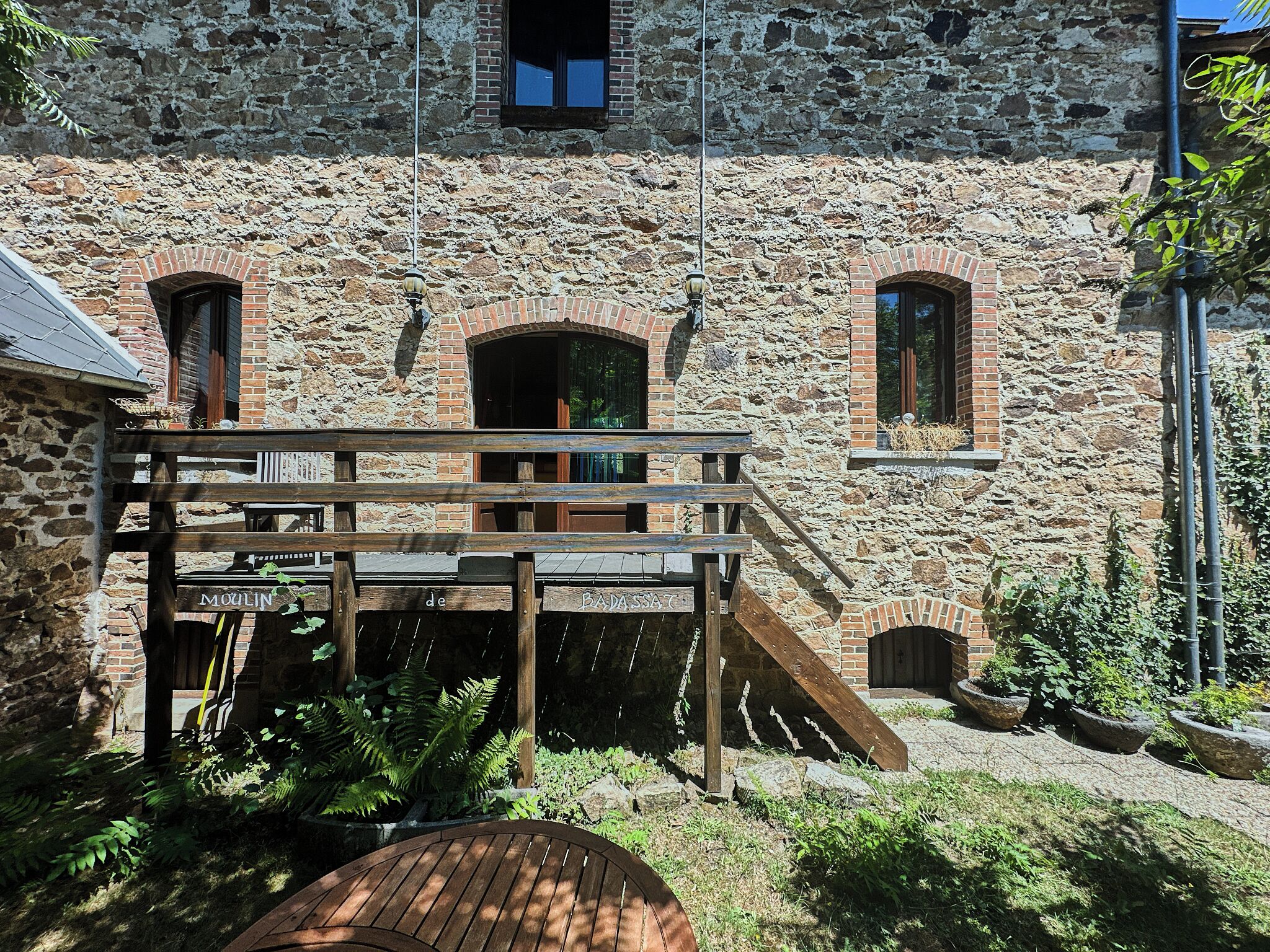 A stone building with a wooden deck and a staircase leading to an entrance.