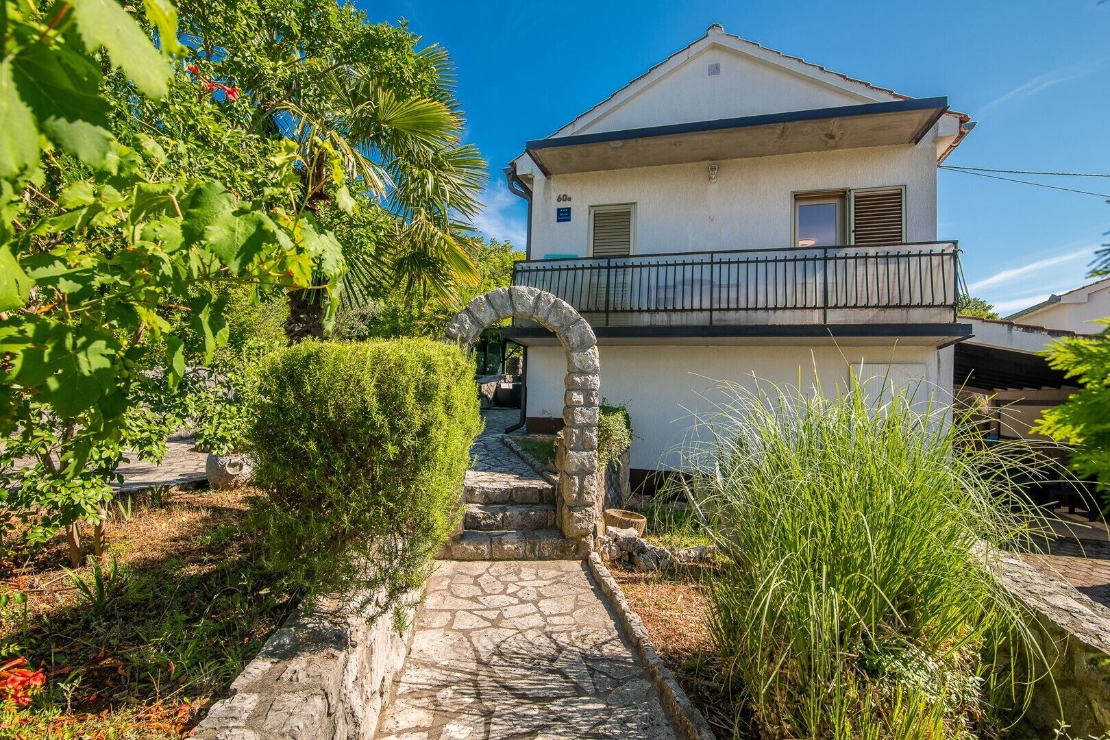A two-story house with a stone pathway leading to the entrance.