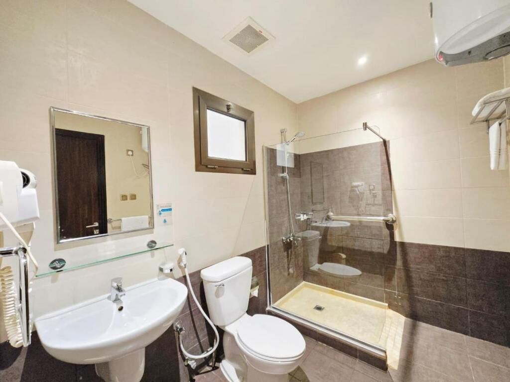 A bathroom with a glass-enclosed shower, a sink, and a toilet.