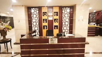 A reception desk with a nameplate, a decorative wall with geometric patterns, and a marble floor.