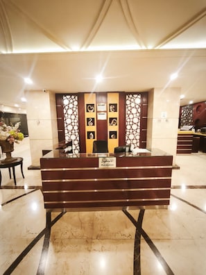 A reception desk with a nameplate, a decorative wall with geometric patterns, and a marble floor. - Dalo Serviced Apartments (Al Khobar)