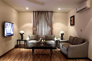A living room with a sofa set, a coffee table, and a TV mounted on the wall. - Dalo Serviced Apartments (Al Khobar)