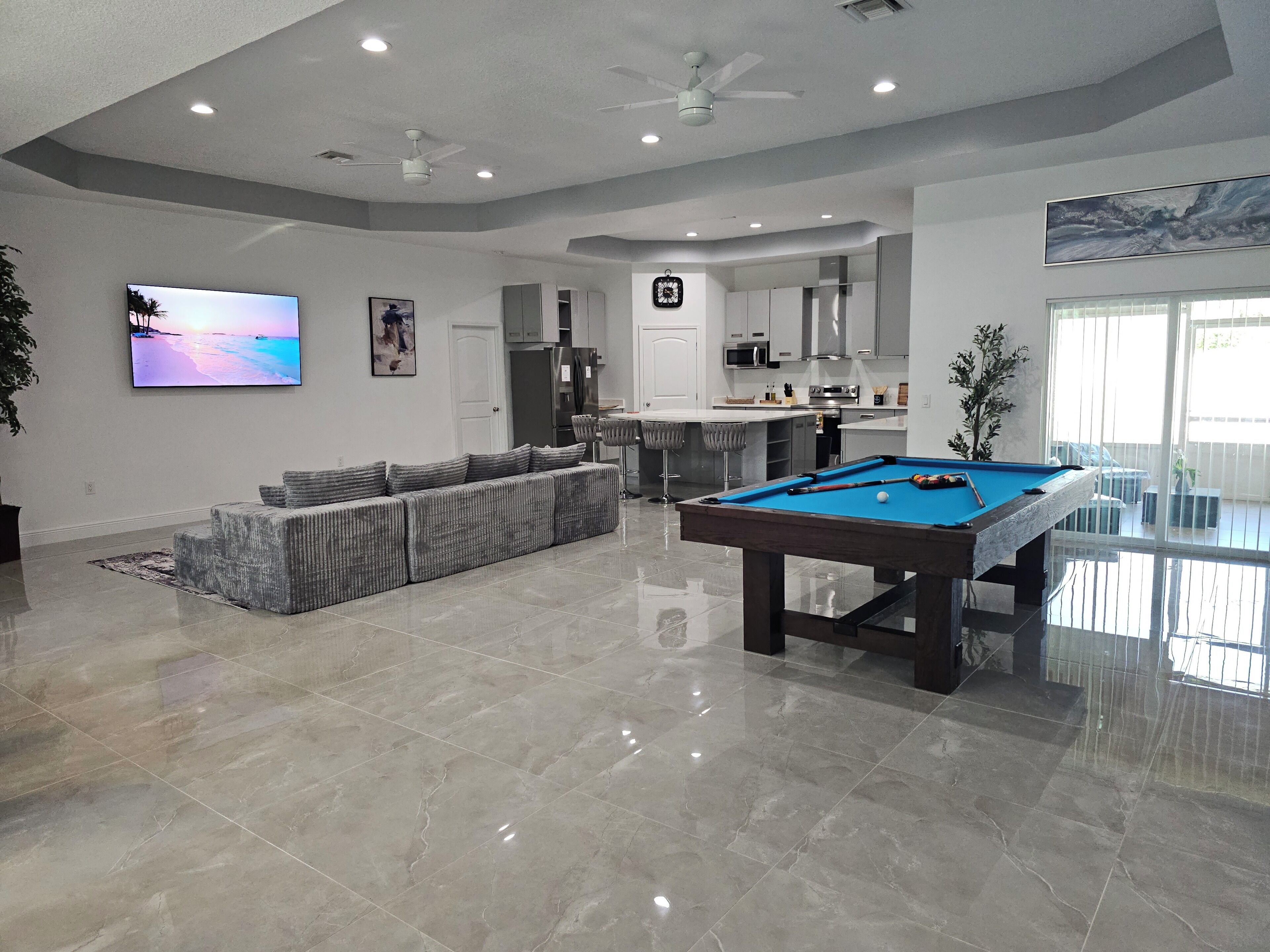 A modern living room with a pool table, a sofa, and a flat-screen TV.