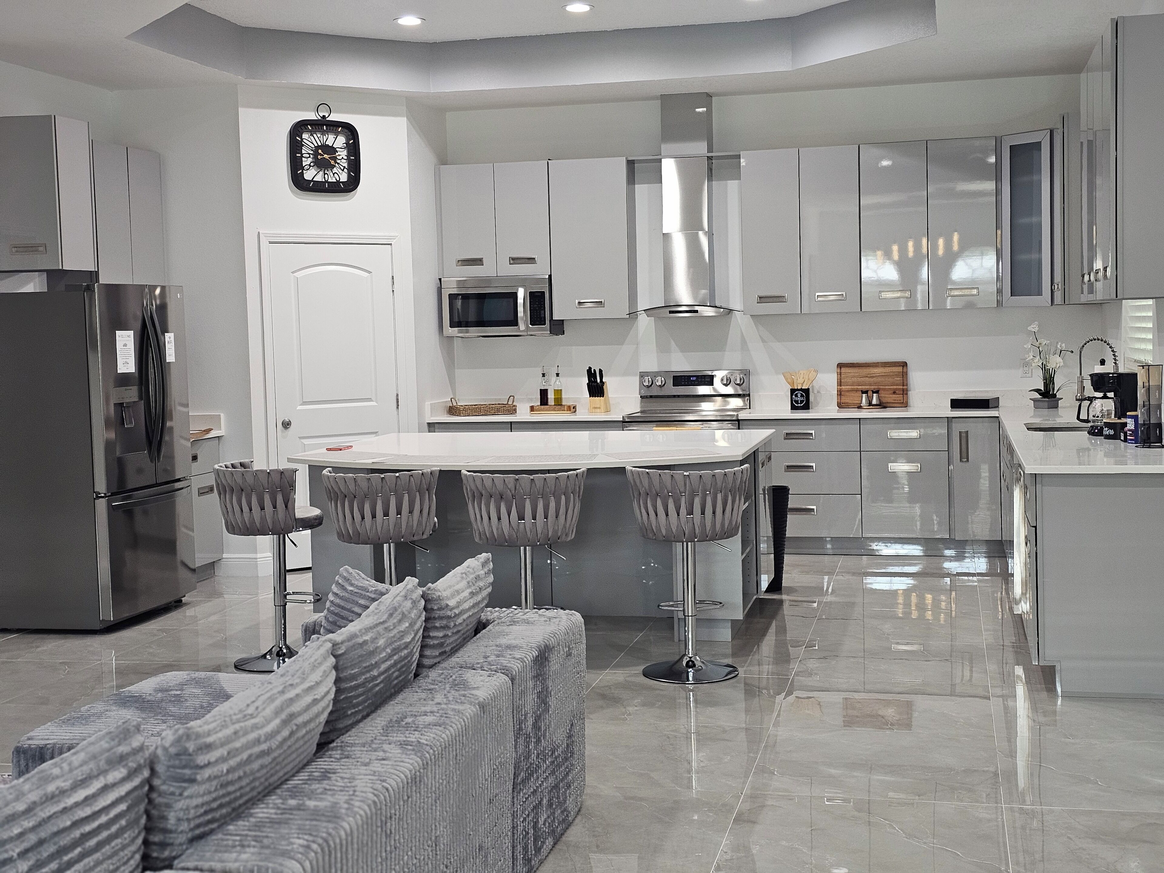 A modern kitchen with stainless steel appliances, a central island with bar stools, and a built-in oven.