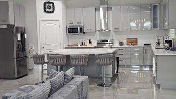 A modern kitchen with stainless steel appliances, a central island with bar stools, and a built-in oven.