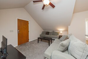 Ein Wohnzimmer mit Deckenventilator, einer Couch, einem Couchtisch und einem Fernseher.