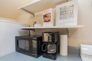 Eine Küchenzeile mit Mikrowelle, Kaffeemaschine und einem Regal mit Kochbüchern.