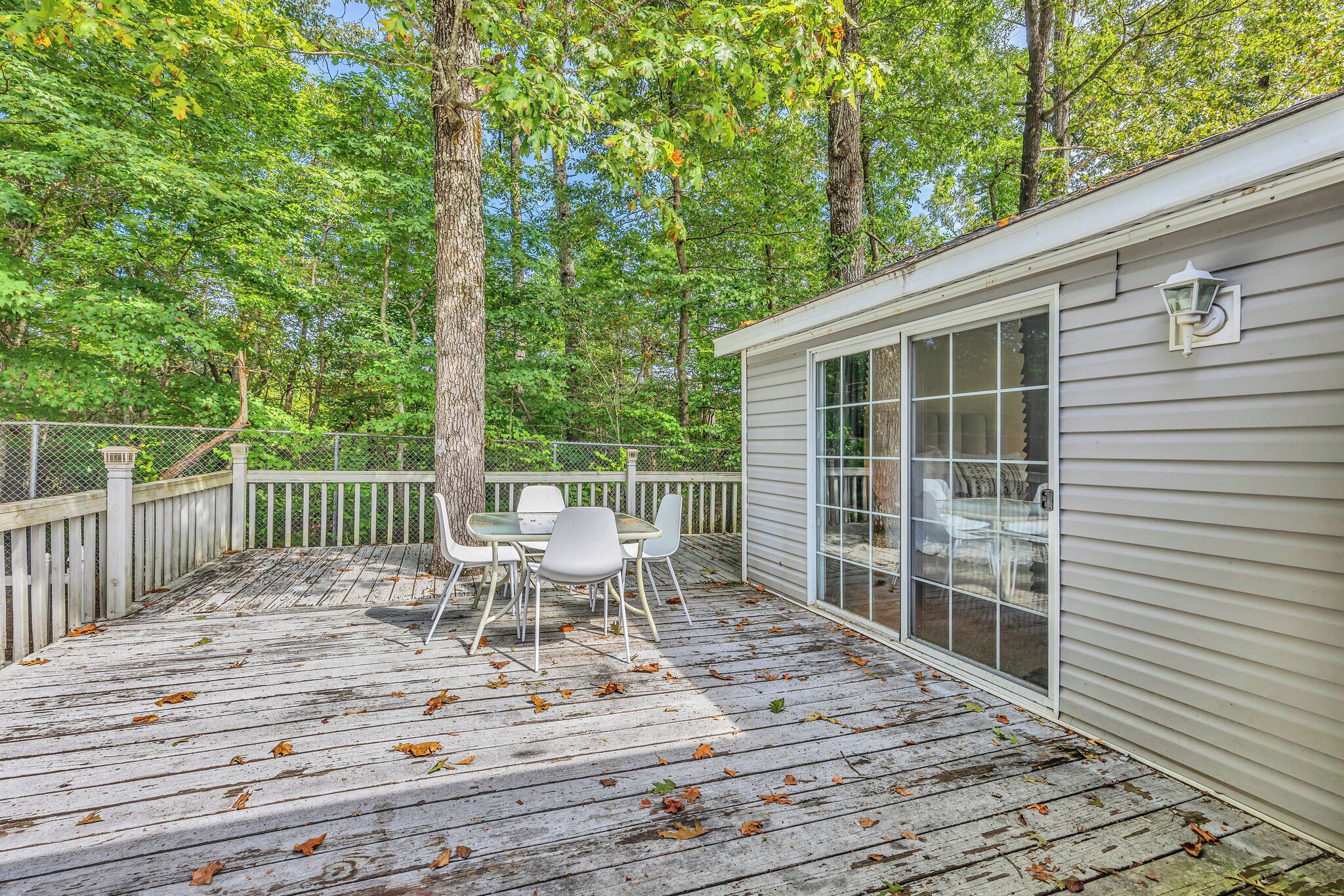 A covered deck with a table and chairs, surrounded by trees.