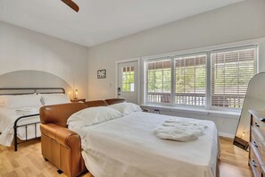 Un dormitorio con cama, una silla, un tocador y una ventana con persianas.