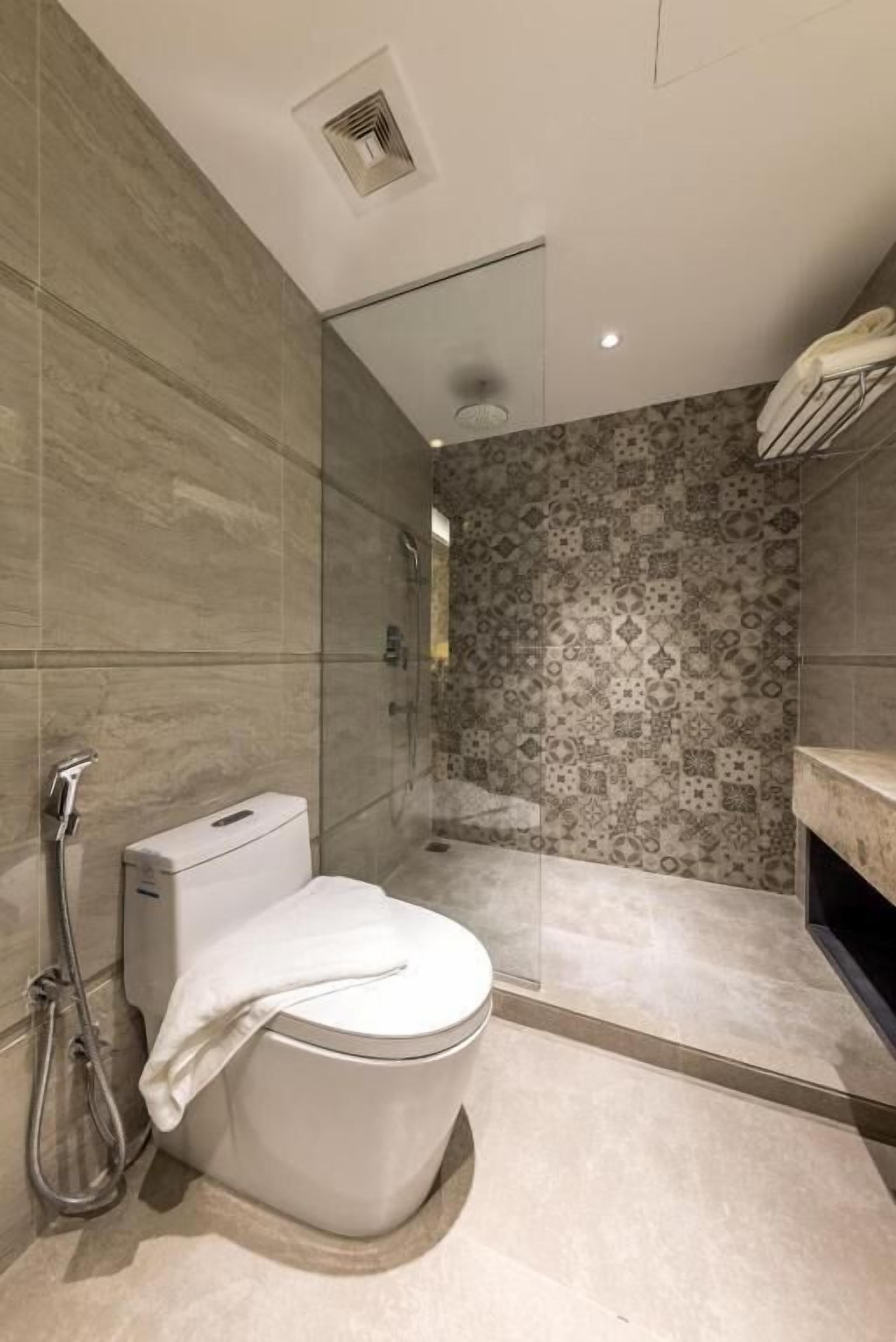 Ein modernes Badezimmer mit Toilette, Dusche und Wandfliesen mit Muster.