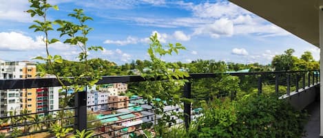 A balcony with a view of a cityscape, including buildings and greenery.