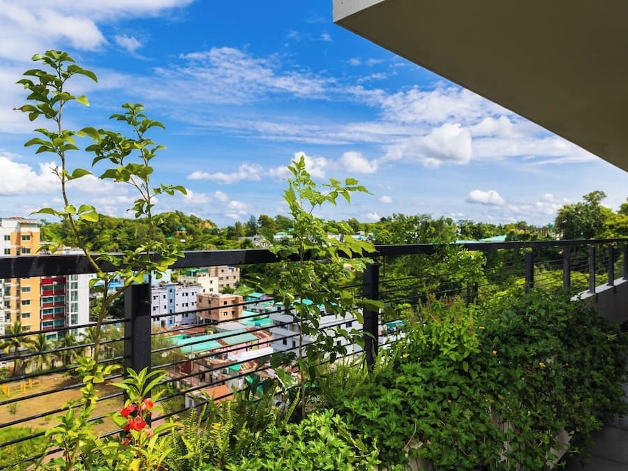A balcony with a view of a cityscape, including buildings and greenery.