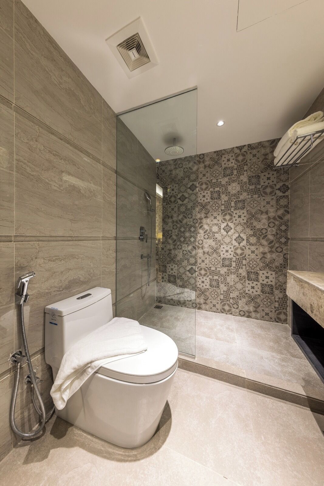 A modern bathroom with a toilet, shower, and glass-enclosed shower area.