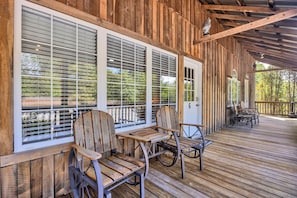 A wooden deck with two Adirondack chairs and a table, a covered porch, and a door with a number. - Brand New, Adorable Suite Near the Caverns! (Monteagle)