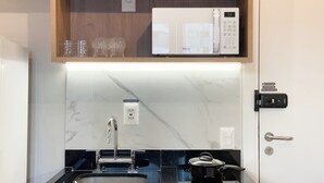 A modern kitchen with a built-in microwave, a sink, and a stove. - Botaní (São Paulo)