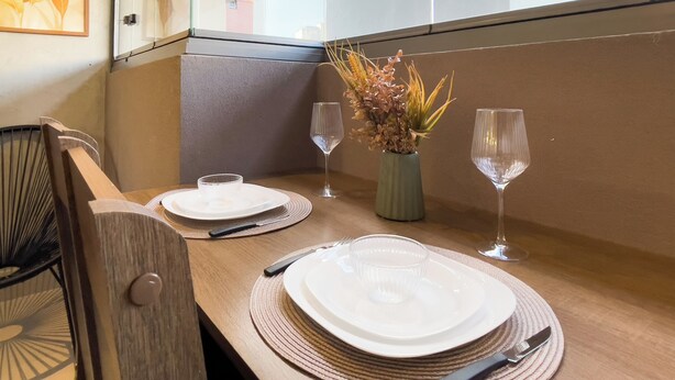 A dining table set with plates, cutlery, and a vase with flowers. - Botaní (São Paulo)