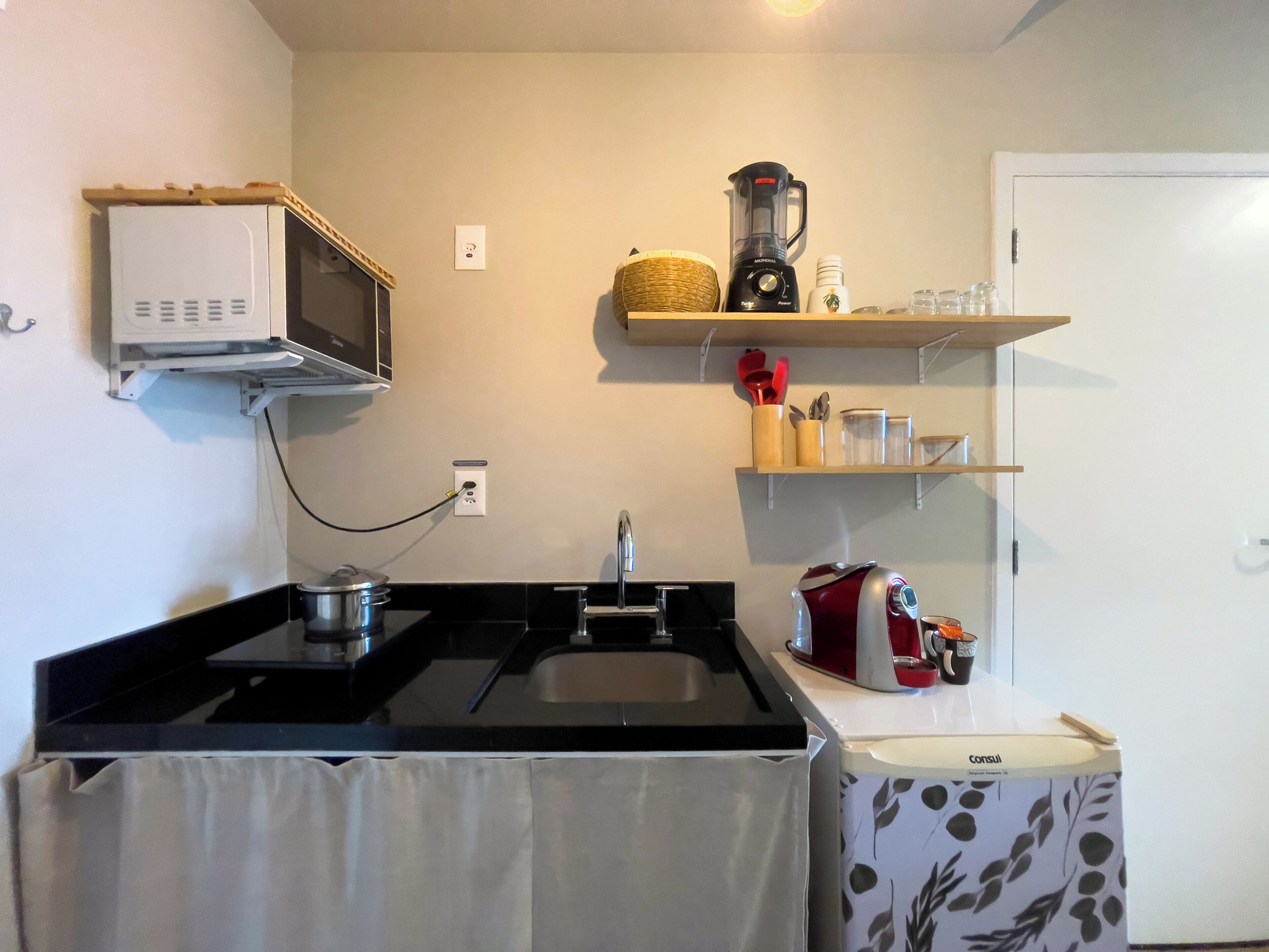 A kitchen with a microwave, a sink, a blender, and a coffee maker.