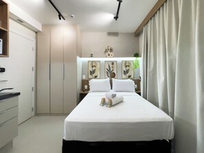 A hotel room with a bed, a wardrobe, a desk, and a nightstand.