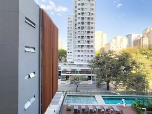 Un edificio moderno con zona de piscina, que incluye sillas de descanso y una piscina pequeña.