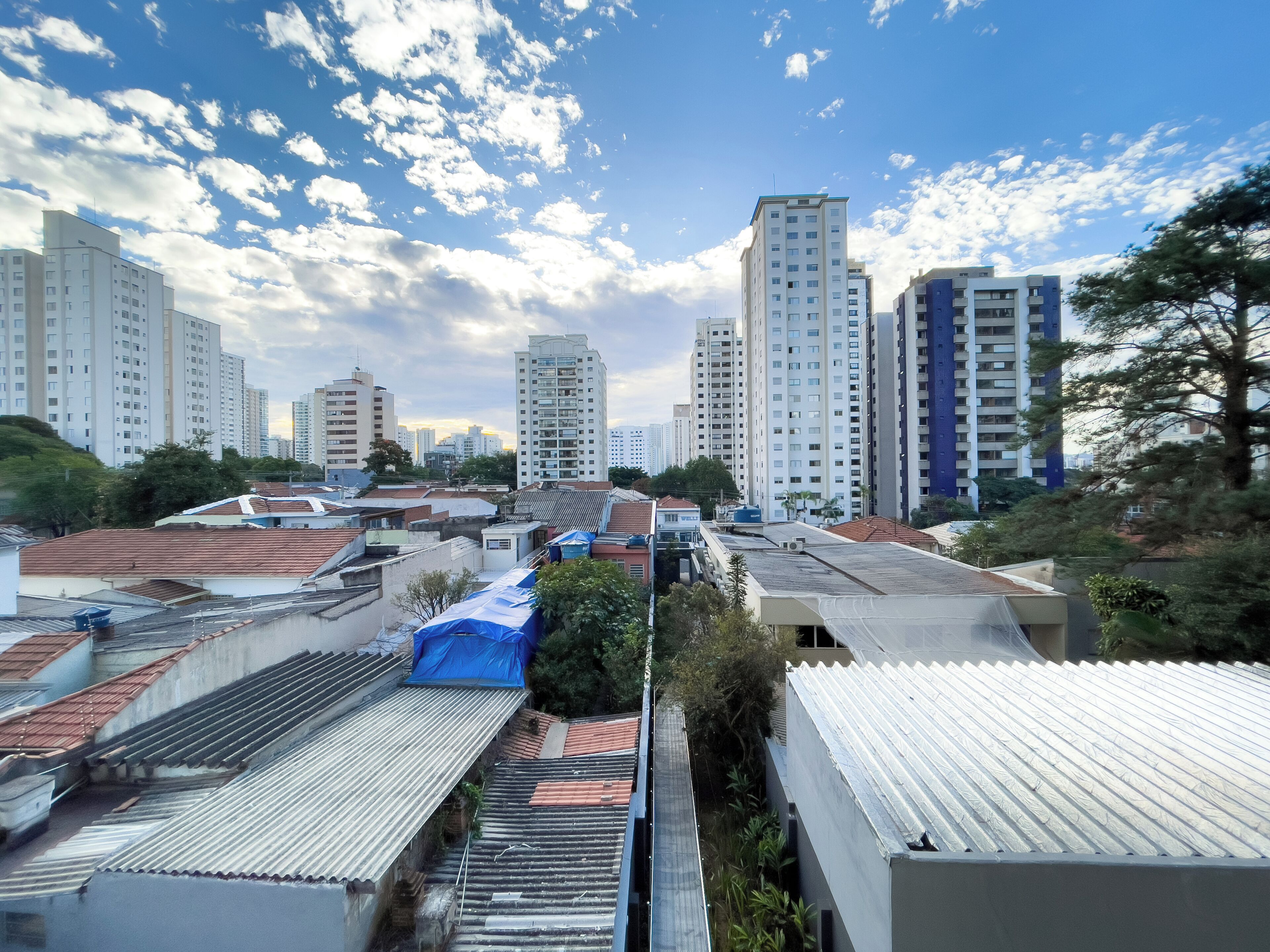 A residential area with multiple high-rise buildings, flat-roofed houses, and a clear sky.