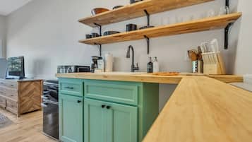 A kitchen with wooden shelves, a sink, and a green cabinet.