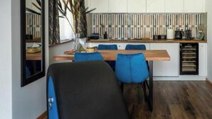 Una cocina moderna con comedor, que incluye una mesa de madera, sillas azules e iluminación colgante.