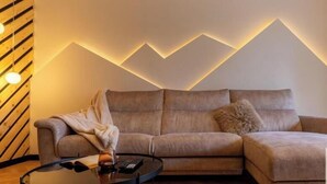 Una sala moderna con un sofá modular, una mesa de centro de vidrio y un diseño de pared original.