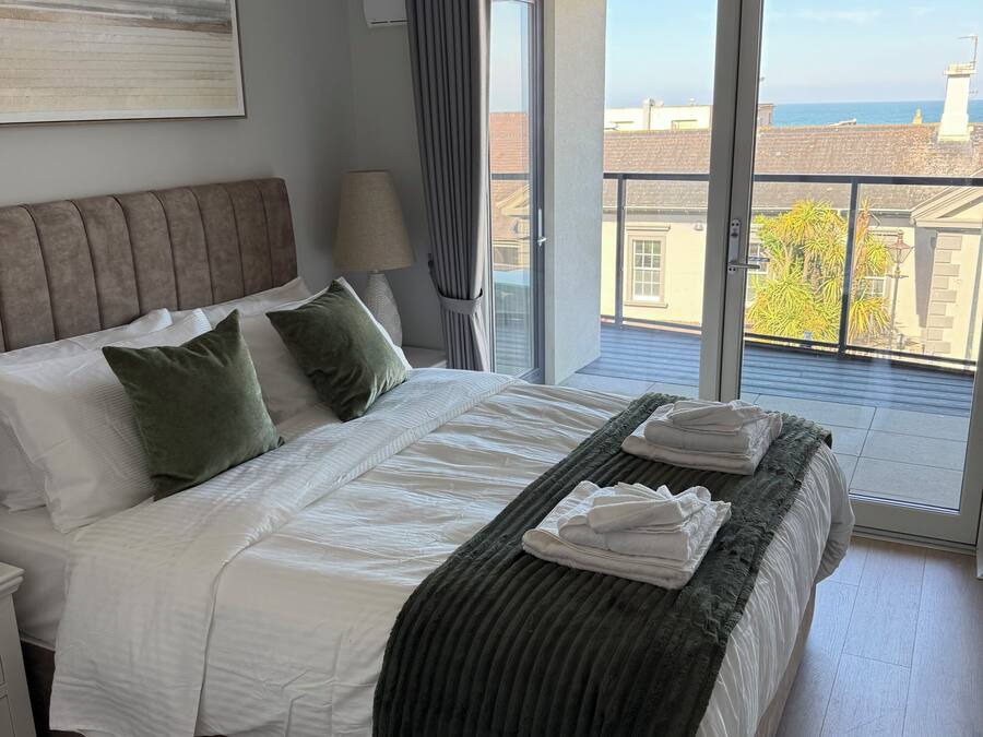 Un dormitorio con una cama grande, vistas al mar y un balcón.