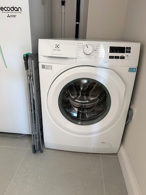 Una lavadora de carga frontal con panel de control, un código QR y una etiqueta que indica que es el modelo 600 SENSICARE de 10kg.