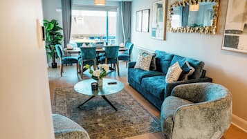 Una sala de estar con sofá, sillones, una mesa de centro y un comedor con sillas y una mesa.