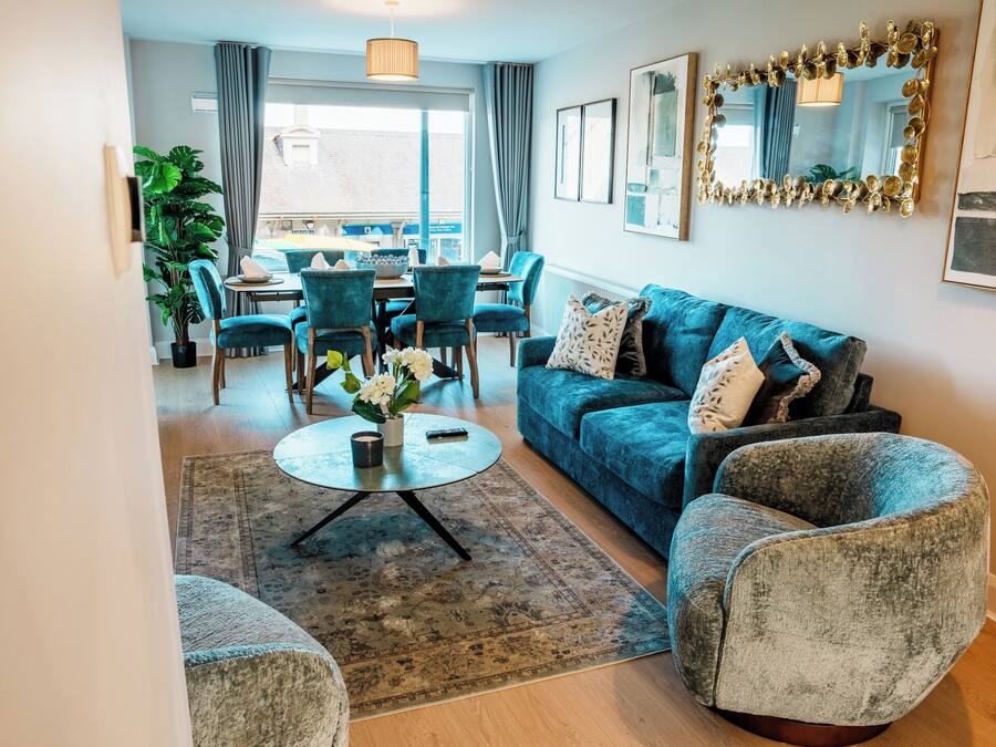 A living room with a sofa, armchairs, a coffee table, and a dining area with chairs and a table.