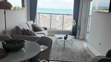 Ein modernes Wohnzimmer mit Meerblick, einer Essecke und einem Sofa mit Zierkissen.