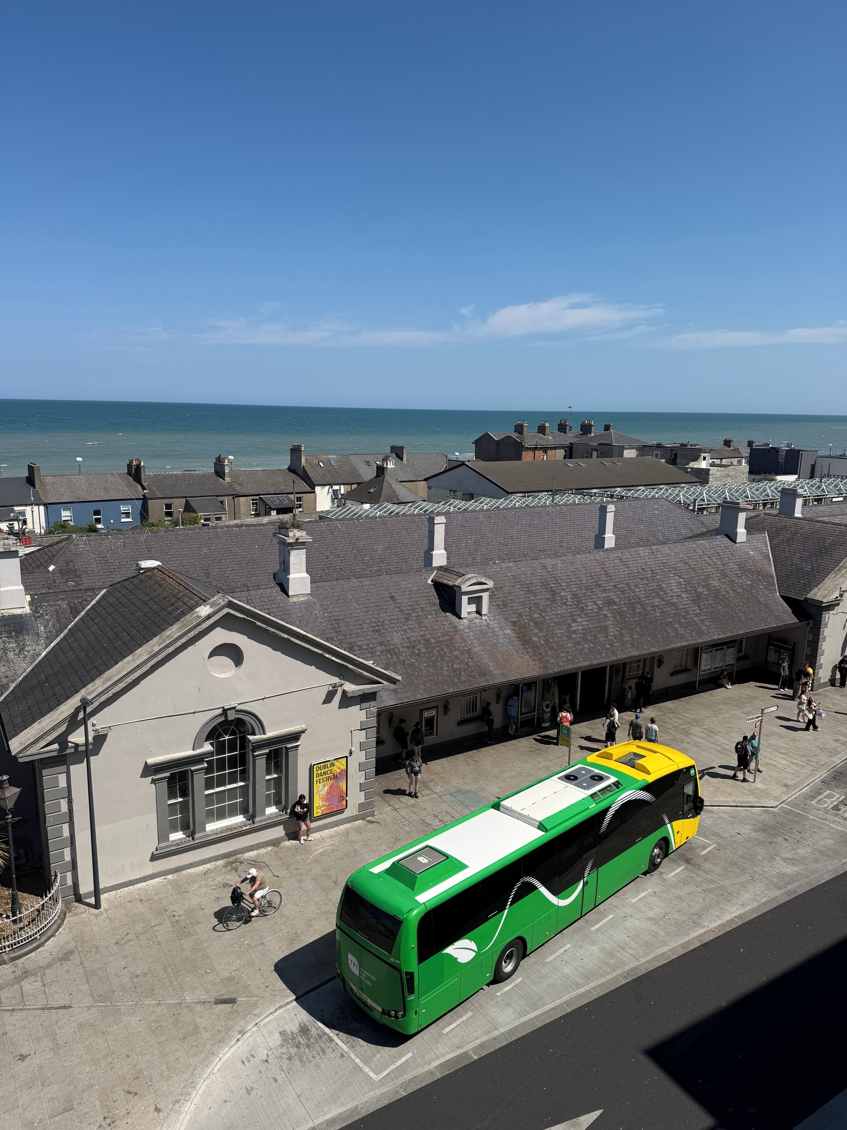 A green bus parked in front of a building with a sign for the Dublin Dance Festival.