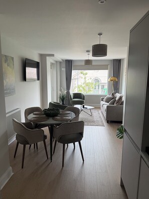 A modern living space with a dining area, a sofa, and a view of the outside. - The International Apartments Bray (Bray)