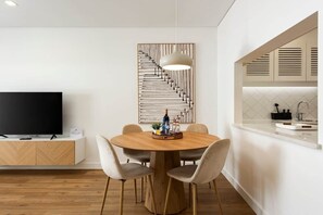 Eine moderne Küche mit Backofen, Essbereich mit rundem Tisch und Stühlen sowie einem Flachbildfernseher auf einem Holzschrank.