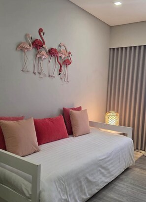 A bedroom with a bed, pillows, a wall-mounted flamingo decoration, a bedside lamp, and a window with curtains. - Buganvilia House Faro | Elegant Urban Retreat (Faro (Sto. António))