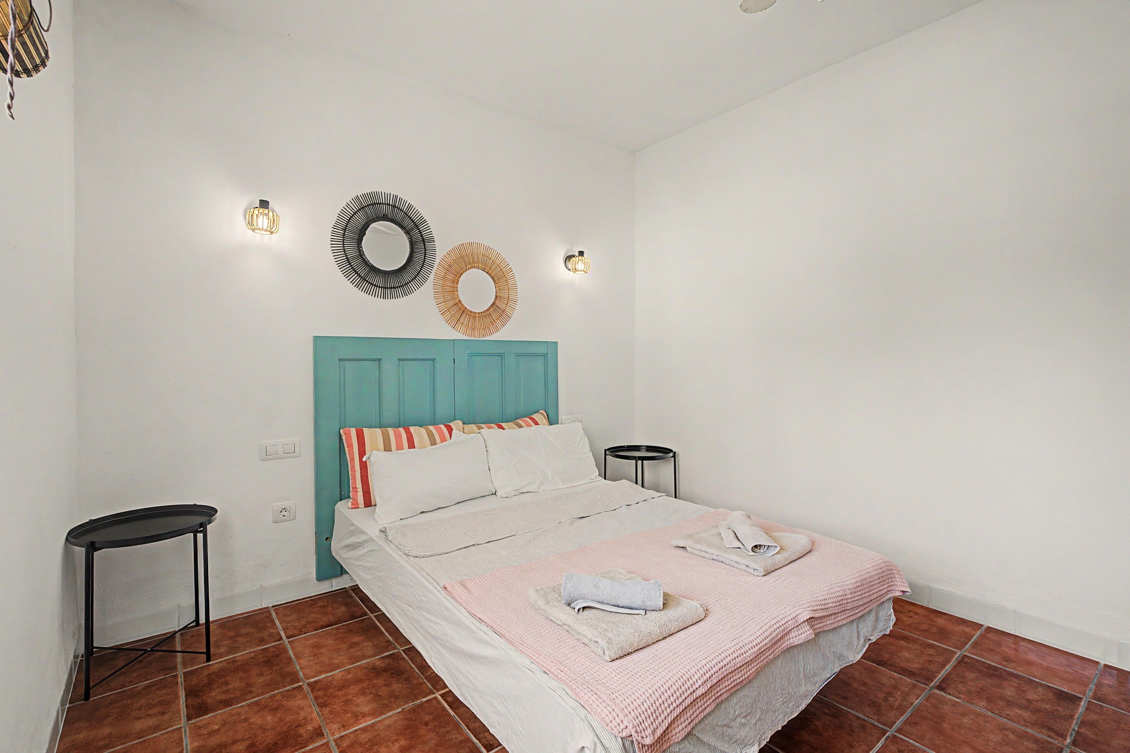 Une chambre à coucher comprenant un lit, deux tables de chevet, un luminaire fixé au mur et un miroir décoratif.