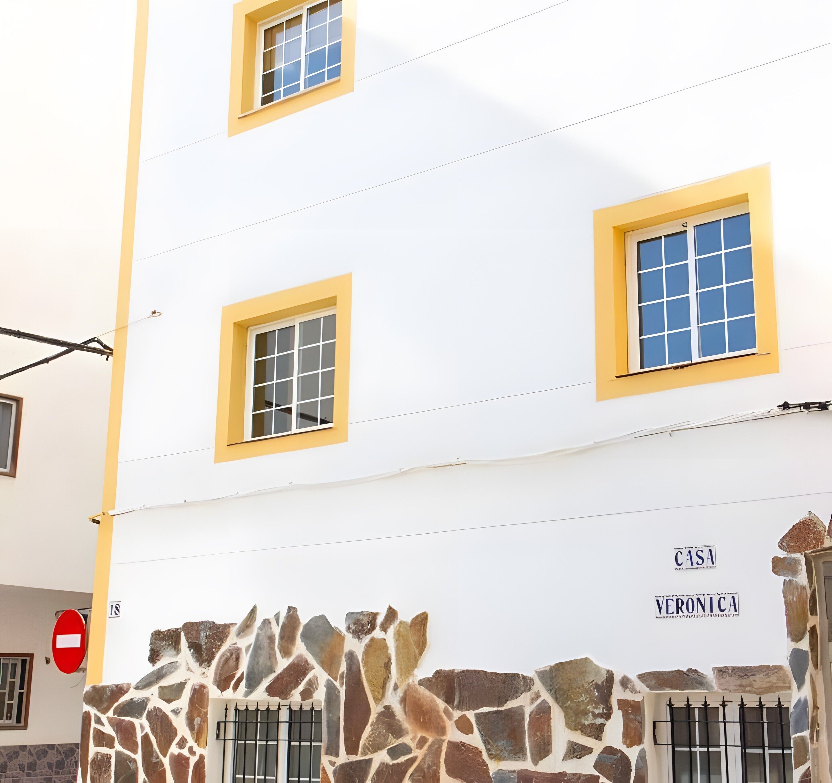 Un edificio con tres ventanas, una pared de piedra y un cartel que dice 'CASA VERONICA'.