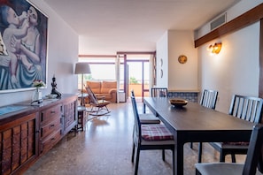 A dining area with a long table, chairs, and a sofa in the background. - Cubo's Playamar Beach Apartment / communal pool / terrace / air conditioning / free Wi-Fi (Torremolinos)