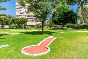 Un jardin bien entretenu, avec un chemin circulaire central, bordé de pelouse soignée et de différents arbres.