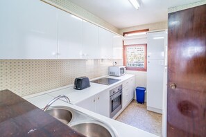 A compact kitchen with white cabinets, a sink, a toaster, and a window with a view of buildings. - Cubo's Playamar Beach Apartment / communal pool / terrace / air conditioning / free Wi-Fi (Torremolinos)