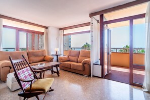 A hotel room with a balcony, a sofa, a chair, and a small table. - Cubo's Playamar Beach Apartment / communal pool / terrace / air conditioning / free Wi-Fi (Torremolinos)