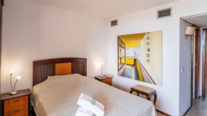 A hotel room with a bed, a nightstand, a painting, a door, and a lamp. - Cubo's Playamar Beach Apartment / communal pool / terrace / air conditioning / free Wi-Fi (Torremolinos)