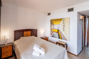 A hotel room with a bed, a nightstand, a painting, a door, and a lamp. - Cubo's Playamar Beach Apartment / communal pool / terrace / air conditioning / free Wi-Fi (Torremolinos)