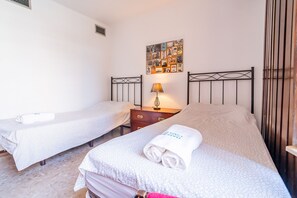Ein Hotelzimmer mit zwei Einzelbetten, einem Nachttisch mit Lampe und einer Wand mit einer Fotocollage.