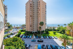 A high-rise building with a parking lot in front, surrounded by greenery and a view of the sea. - Cubo's Playamar Beach Apartment / communal pool / terrace / air conditioning / free Wi-Fi (Torremolinos)